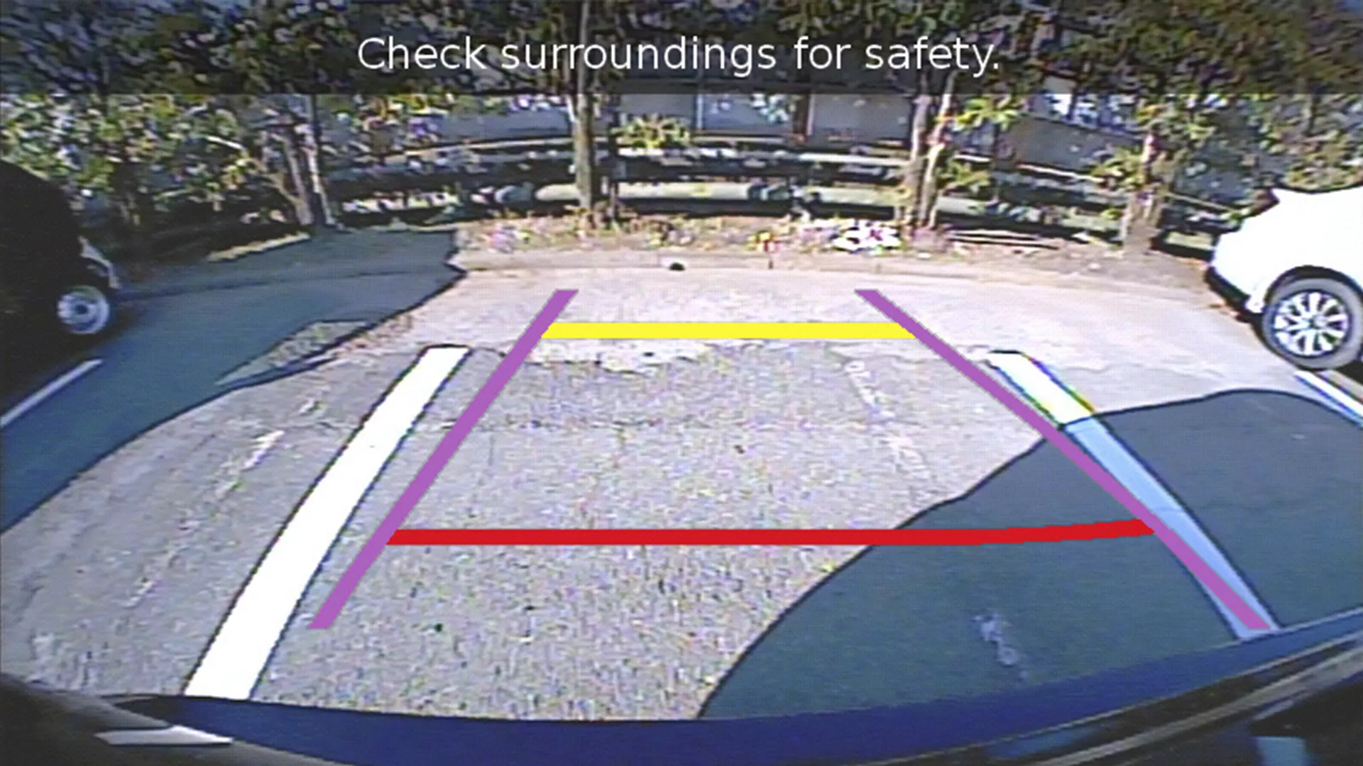 Rear-view camera display of the Suzuki S-Cross showing dynamic parking guidelines and a warning to check surroundings for safety.