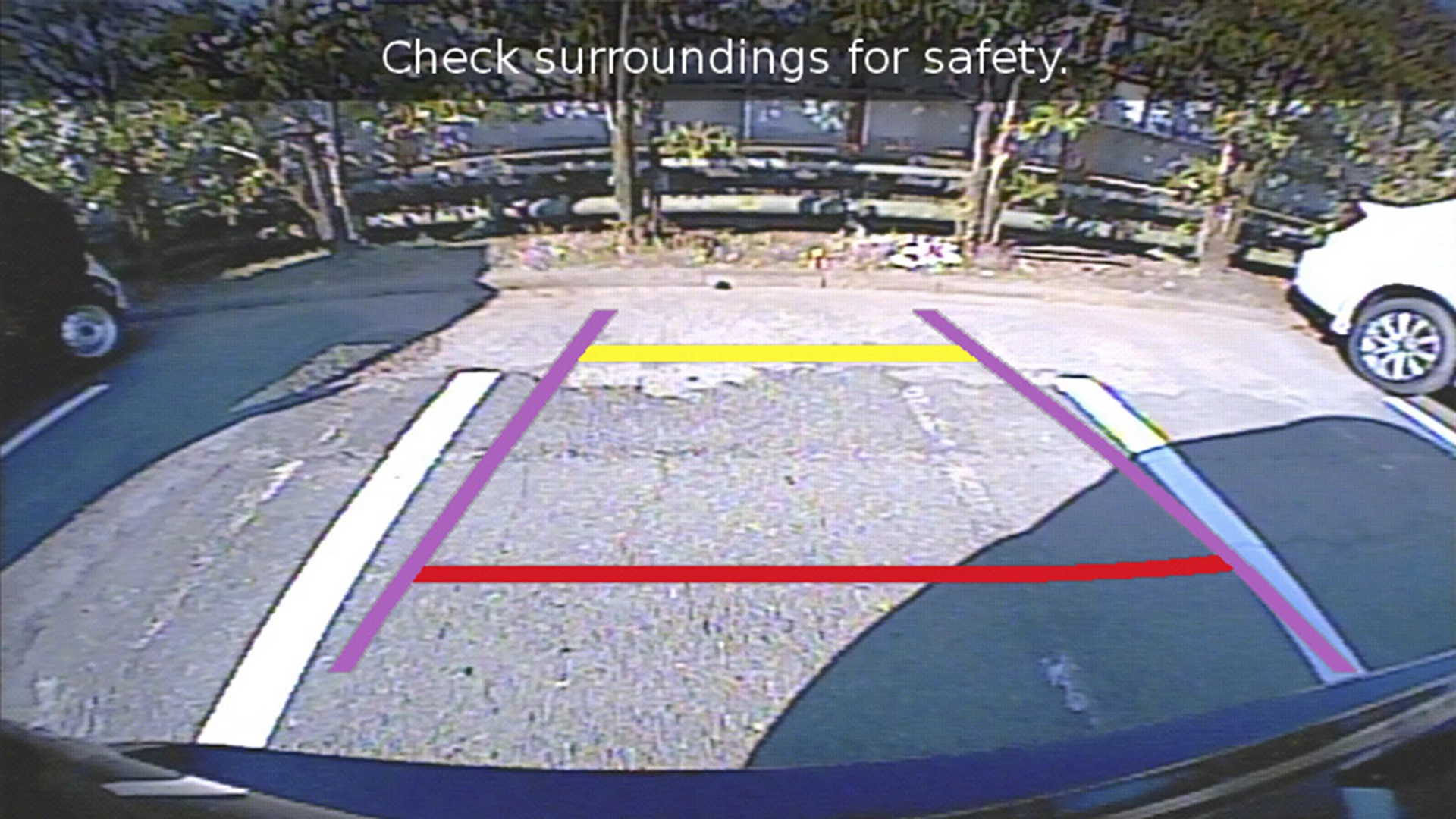 Rear-view camera display of the Suzuki S-Cross showing dynamic parking guidelines and a warning to check surroundings for safety.