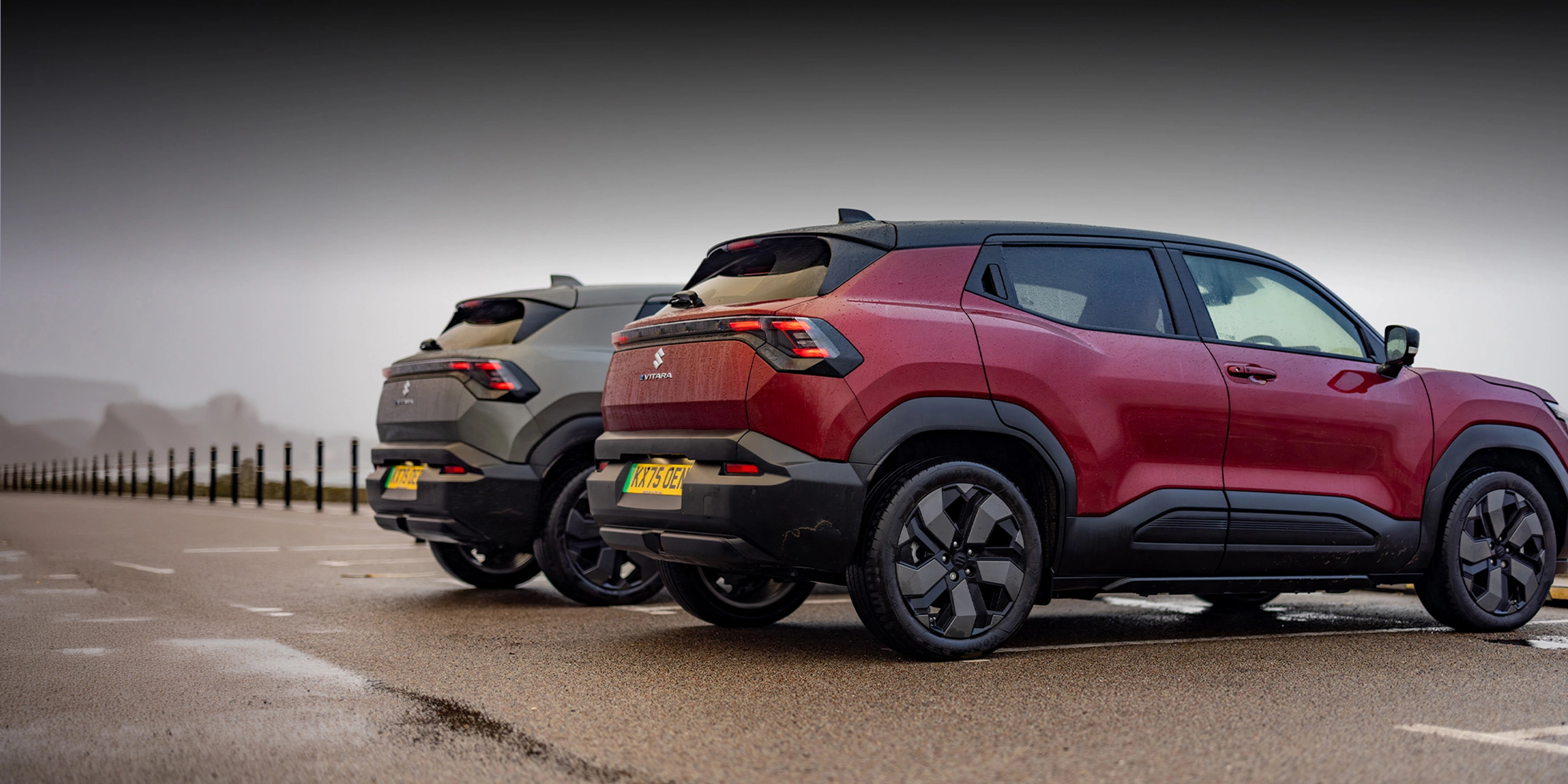 Rear view of red and grey Suzuki e Vitara models parked outdoors
