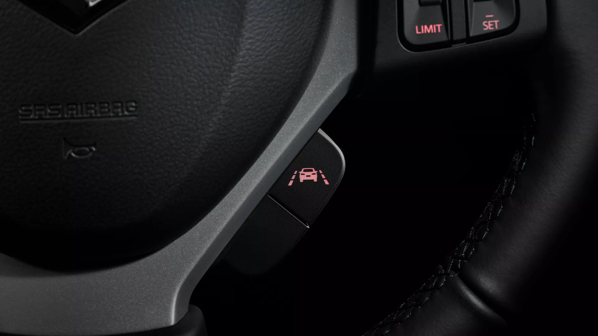 Close-up of the Suzuki S-Cross steering wheel button used to activate the Lane Departure Prevention system, illuminated with a lane marking and vehicle icon.