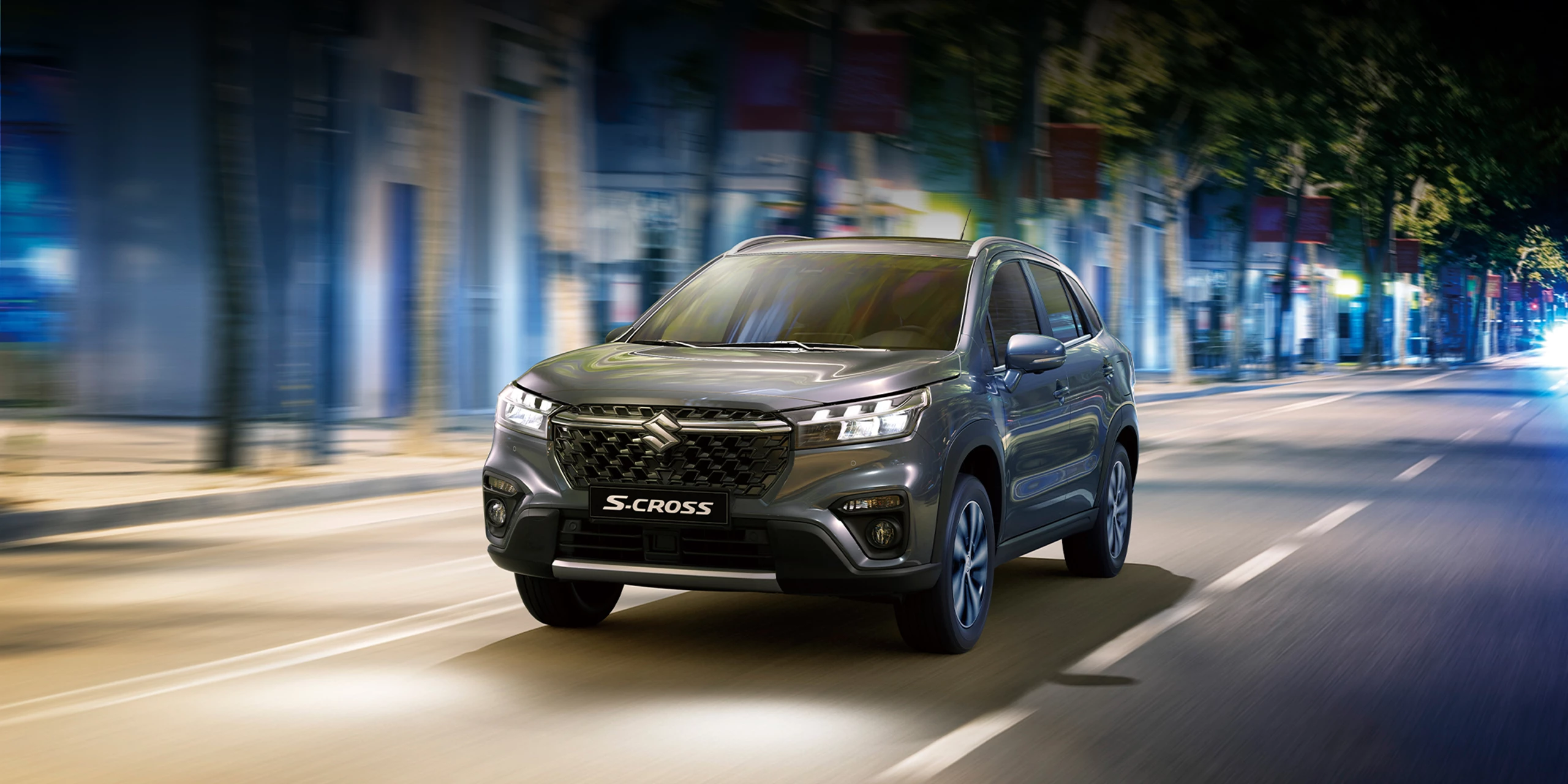 Grey Suzuki S-Cross driving through a city street at night