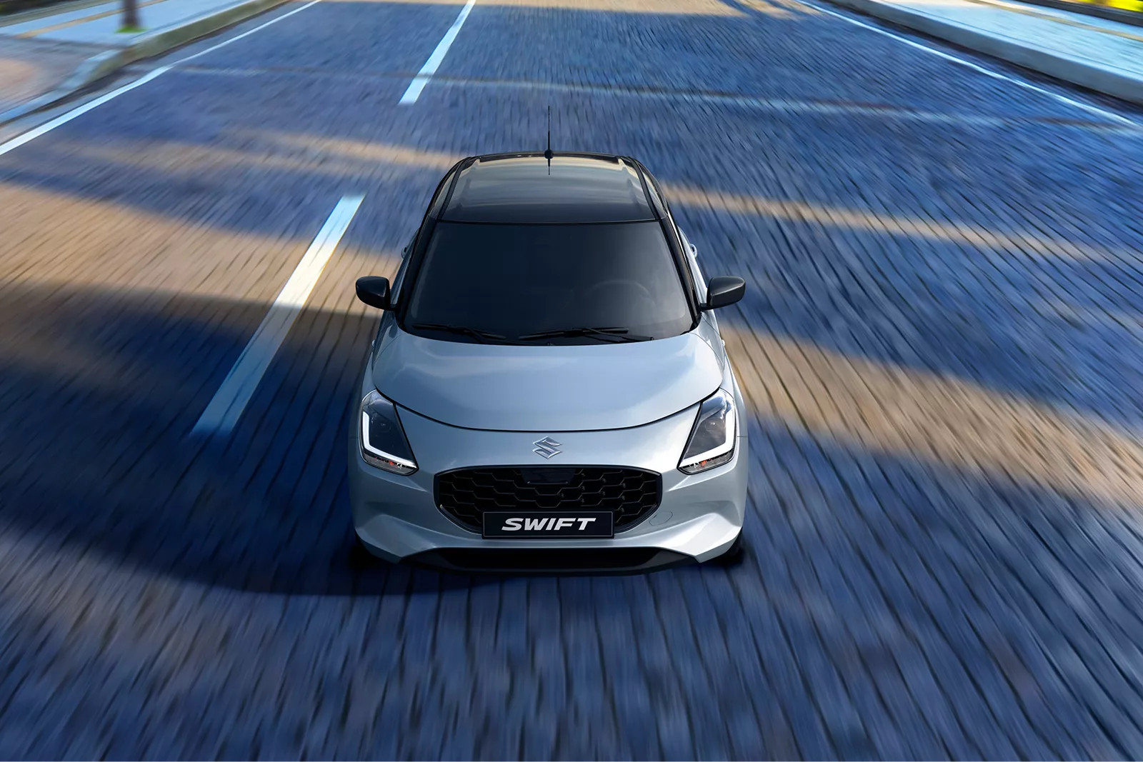 Front view of a grey Suzuki Swift driving on a road