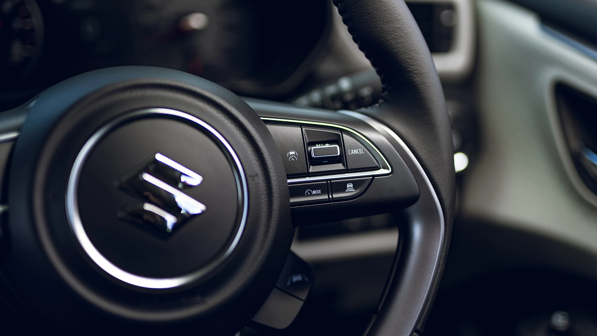 Close-up of the Suzuki Swift steering wheel controls, highlighting the cruise control and speed limiter functions