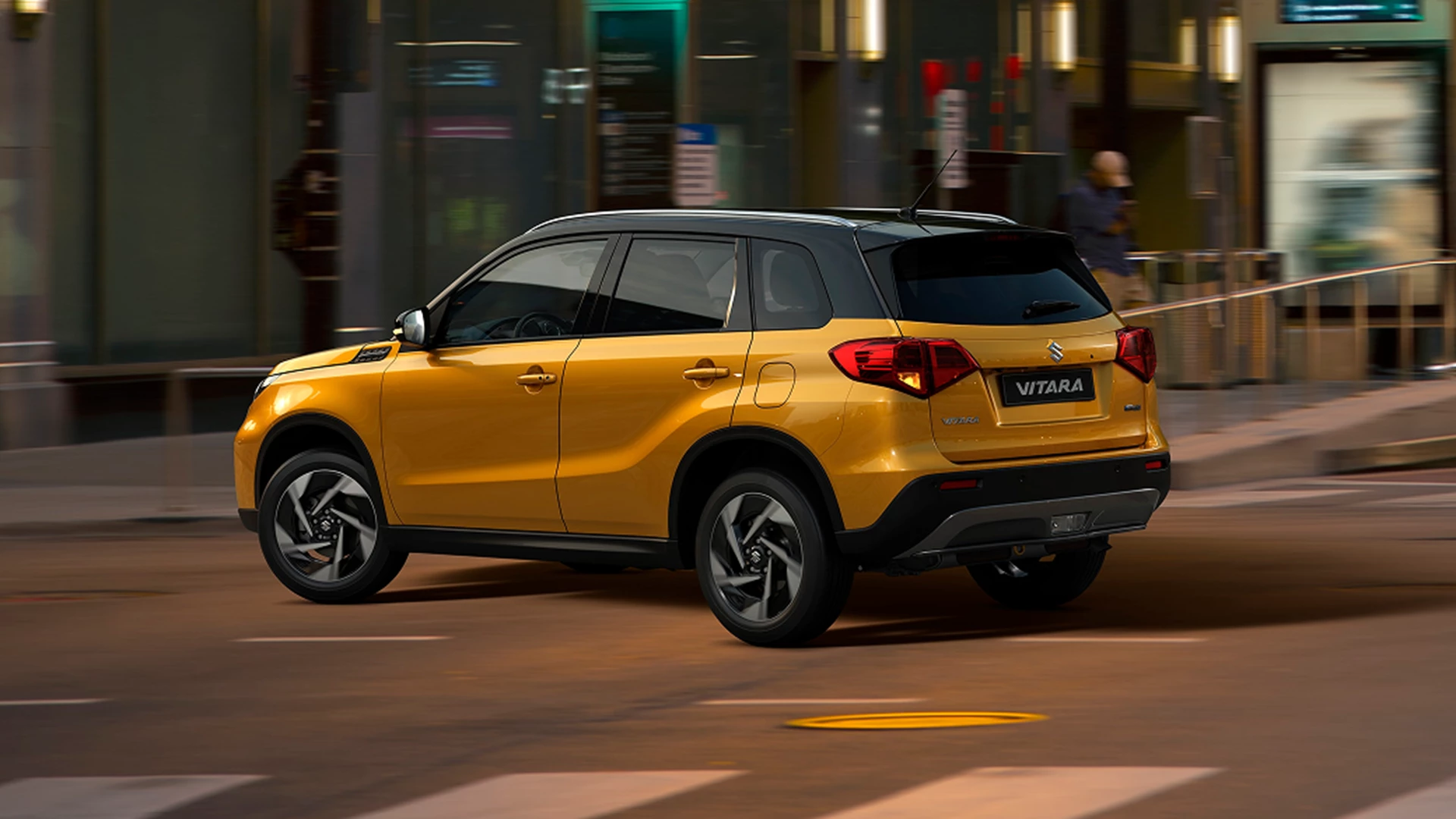 Yellow Suzuki Vitara driving through a city street at night