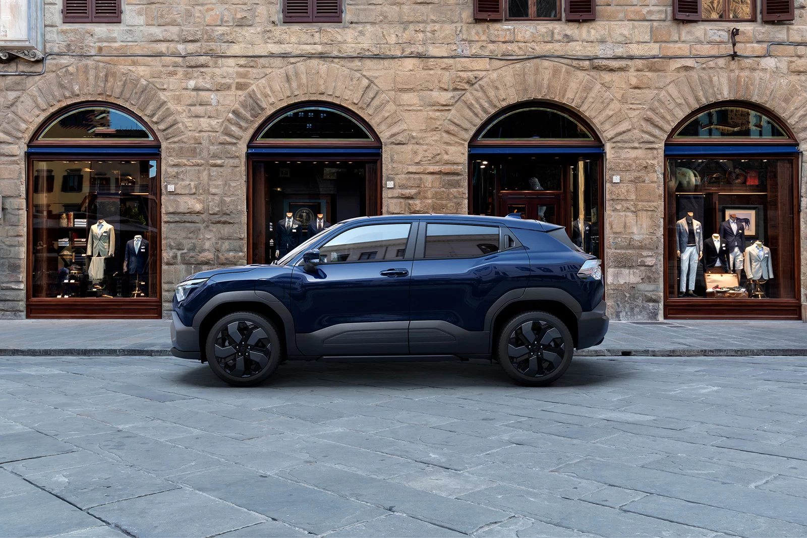 Suzuki e Vitara parked on a stone street in front of boutique storefronts