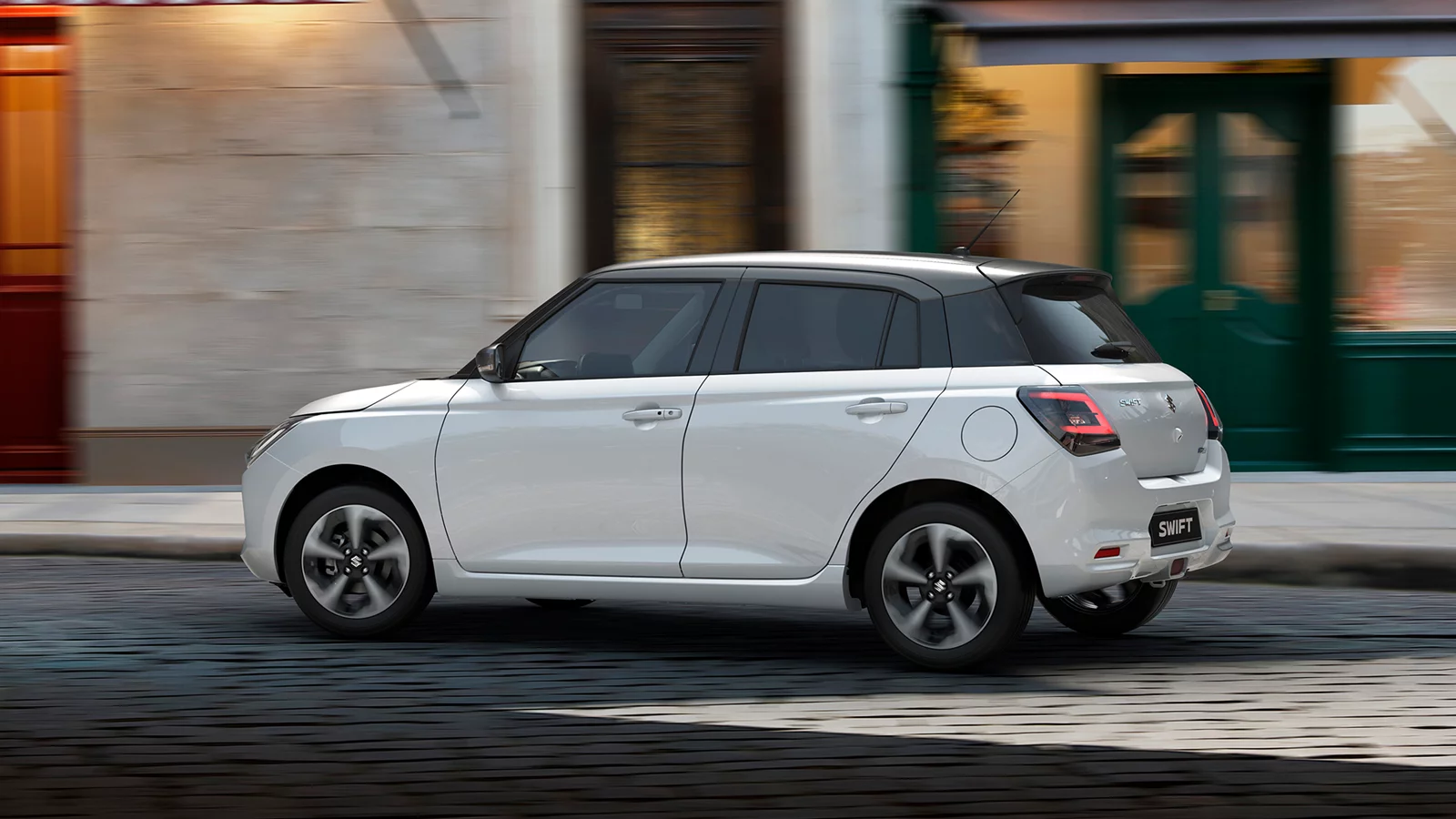 White Suzuki Swift driving through an urban street