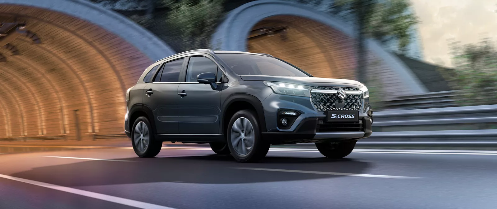 Titan grey Suzuki S-Cross driving past a tunnel entrance, highlighting its dynamic design and urban performance.