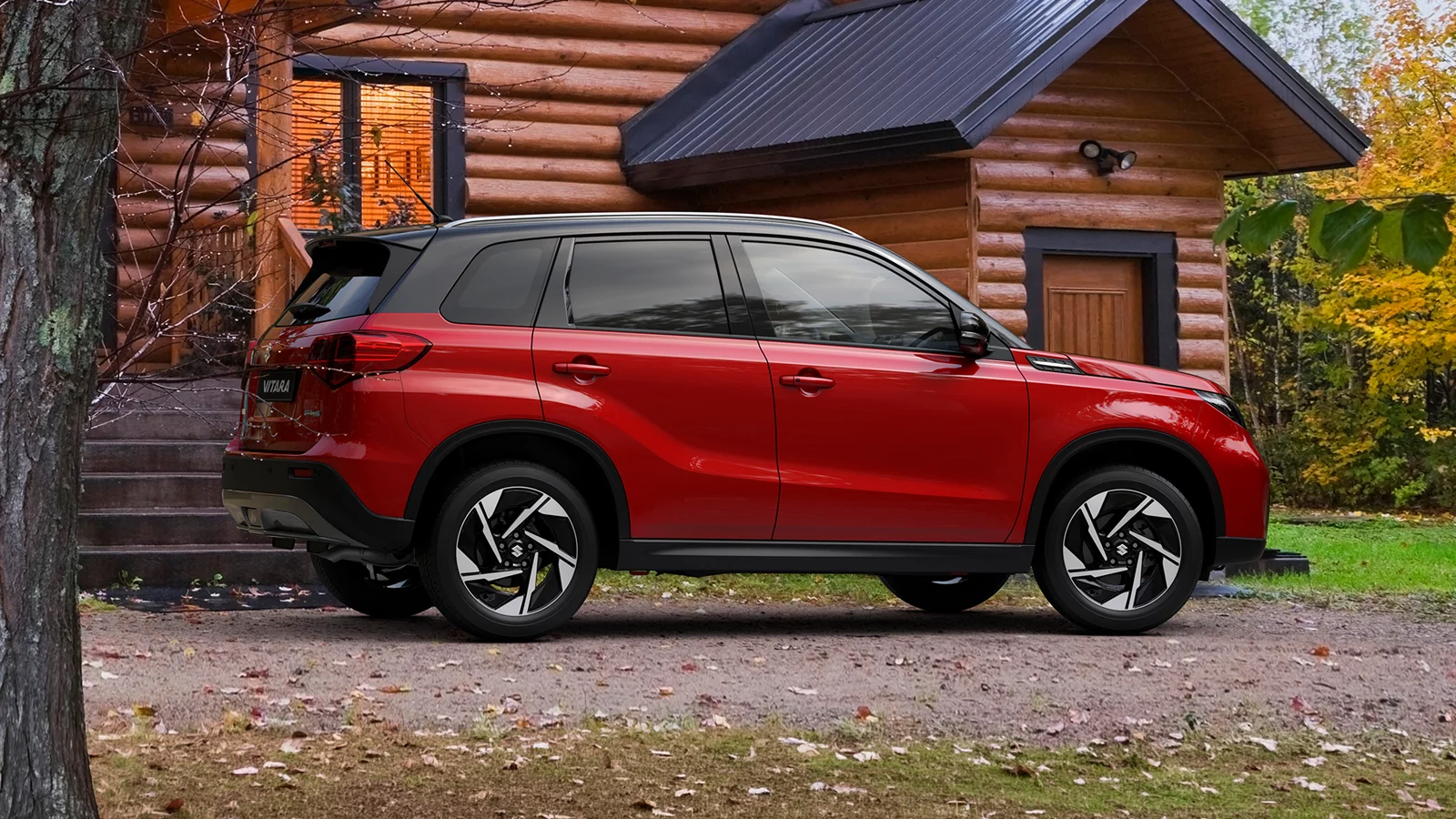 Red Suzuki Vitara parked outside a wooden cabin in a countryside setting