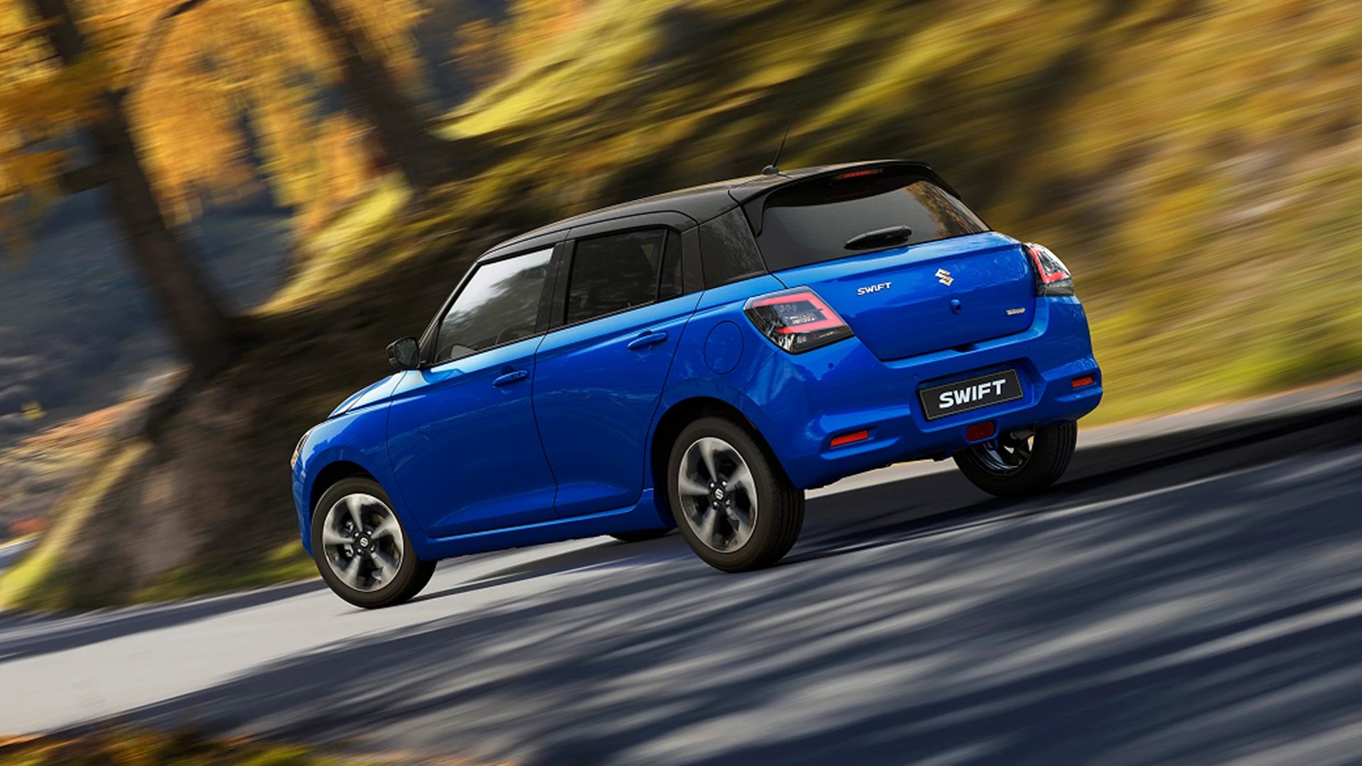 Blue Suzuki Swift driving on a winding countryside road