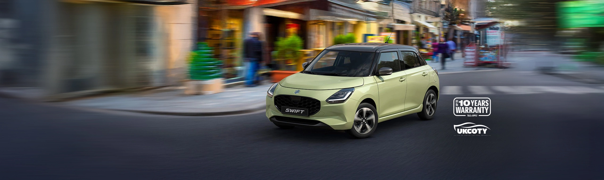 Suzuki Swift driving through a vibrant city street, showcasing its modern design and Top Gear Award badge.