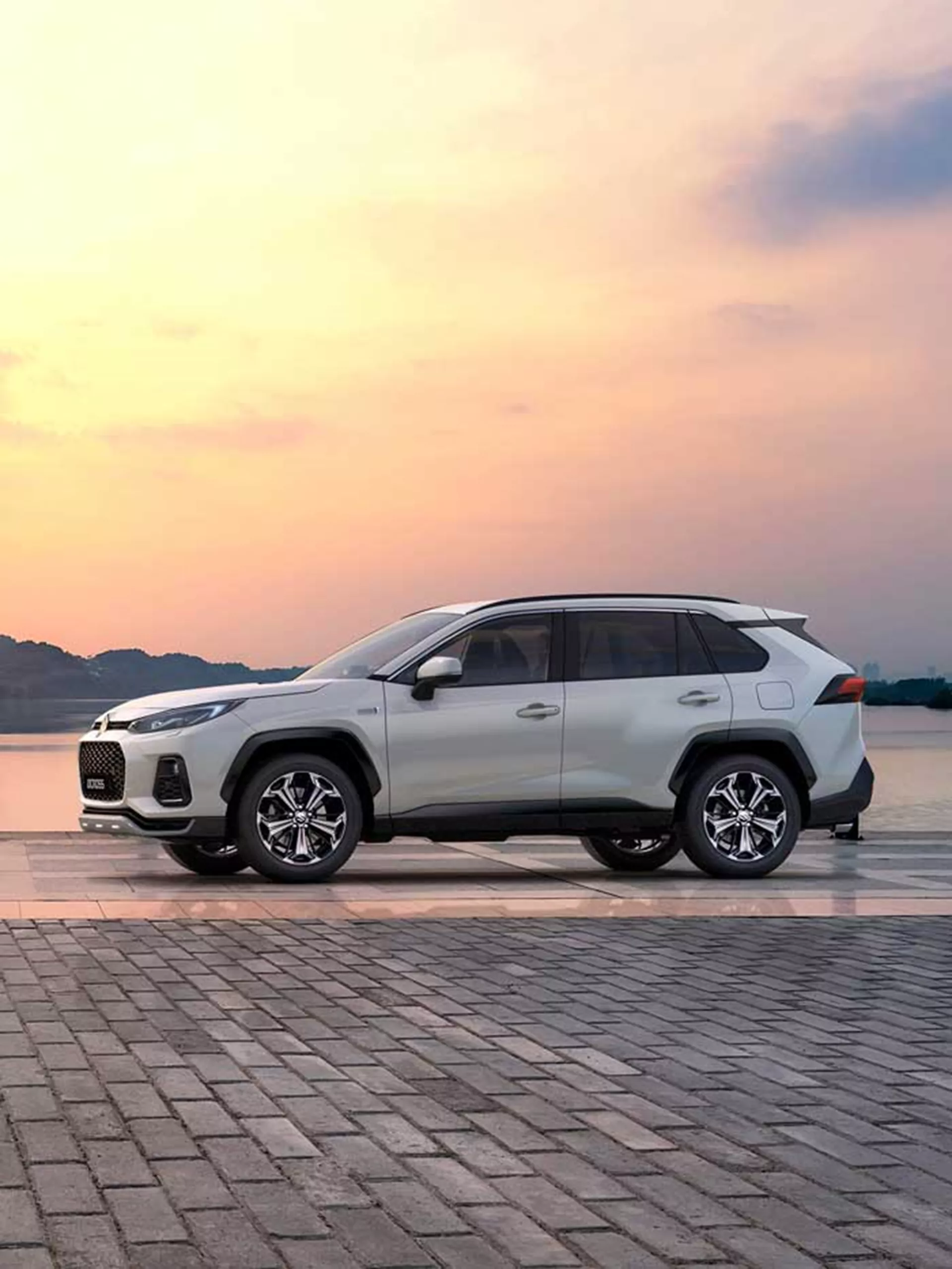 Suzuki Across plug-in hybrid SUV shown at sunset near waterfront.