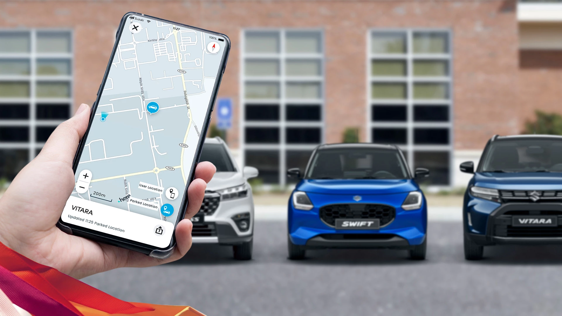 Person using the Suzuki Connect app on a smartphone to locate their parked Vitara, with Swift and Vitara models visible in the background.