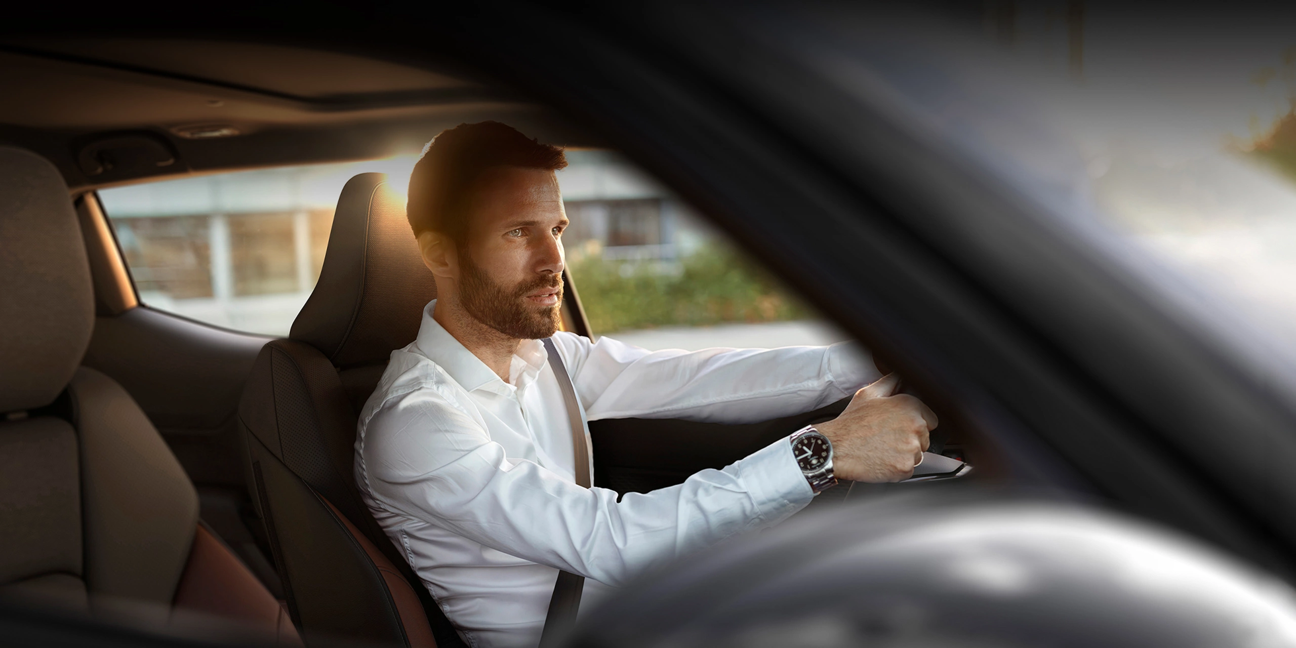 Man driving a car during sunset viewed through the passenger window