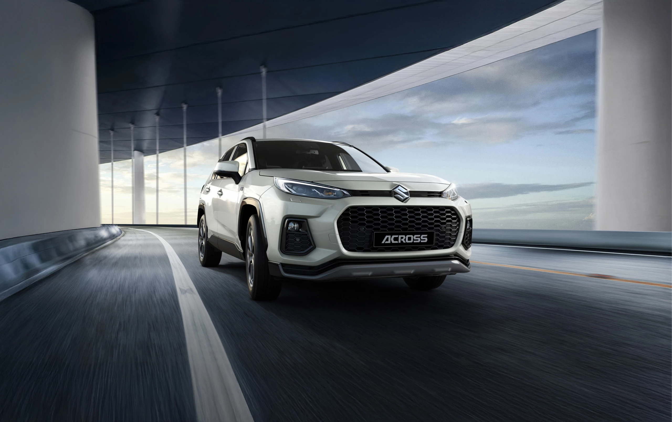 Suzuki Across driving on a curved road, highlighting its bold front grille and dynamic SUV design.