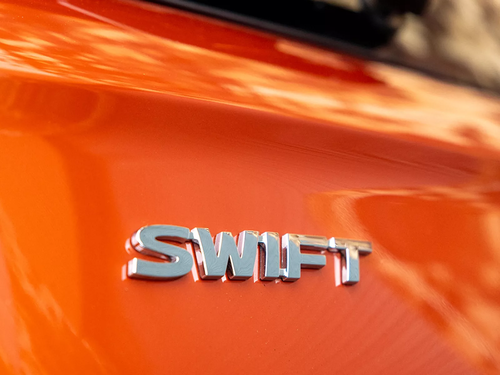 Close-up of the Suzuki Swift rear badge in flame orange pearl metallic