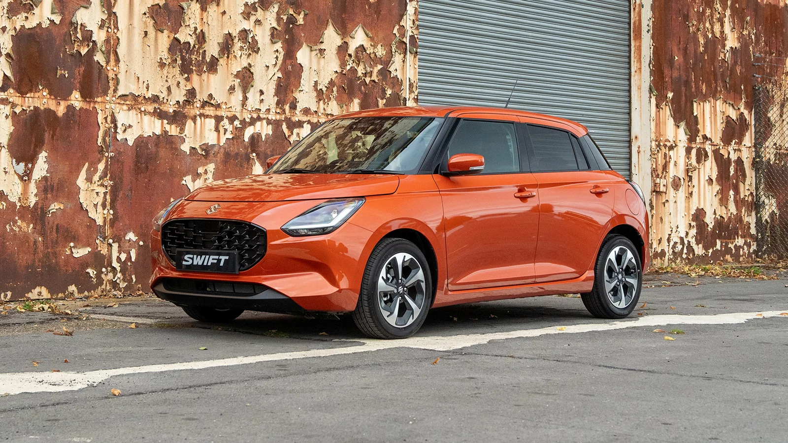 Orange Suzuki Swift parked outside an industrial building