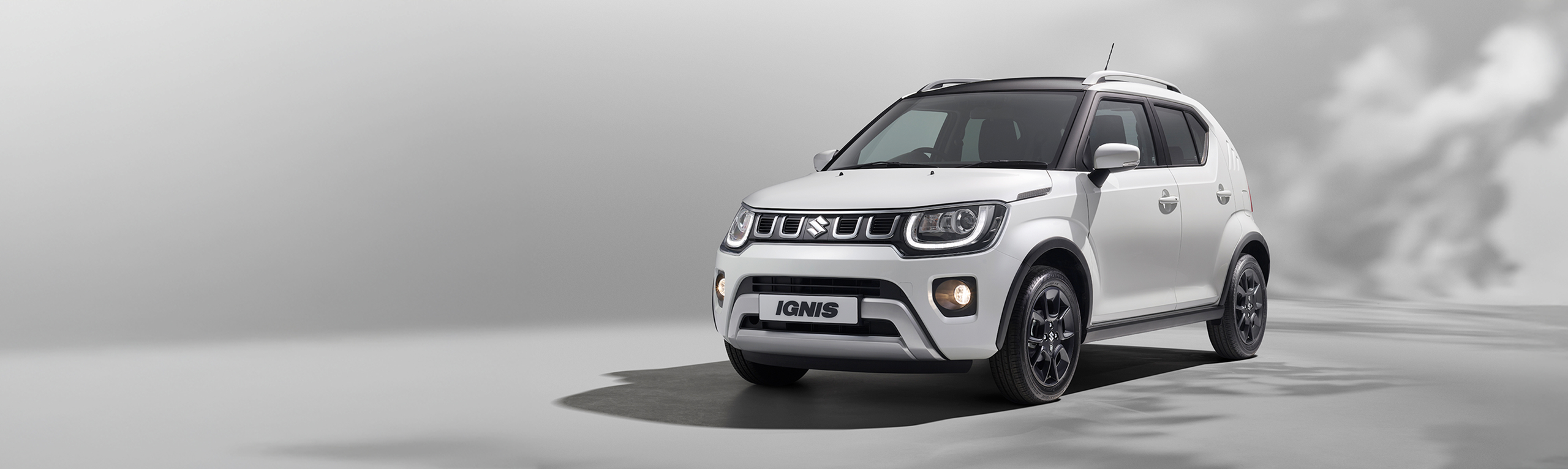 Suzuki Ignis in Pure White Pearl, highlighting LED headlights and black alloy wheels.