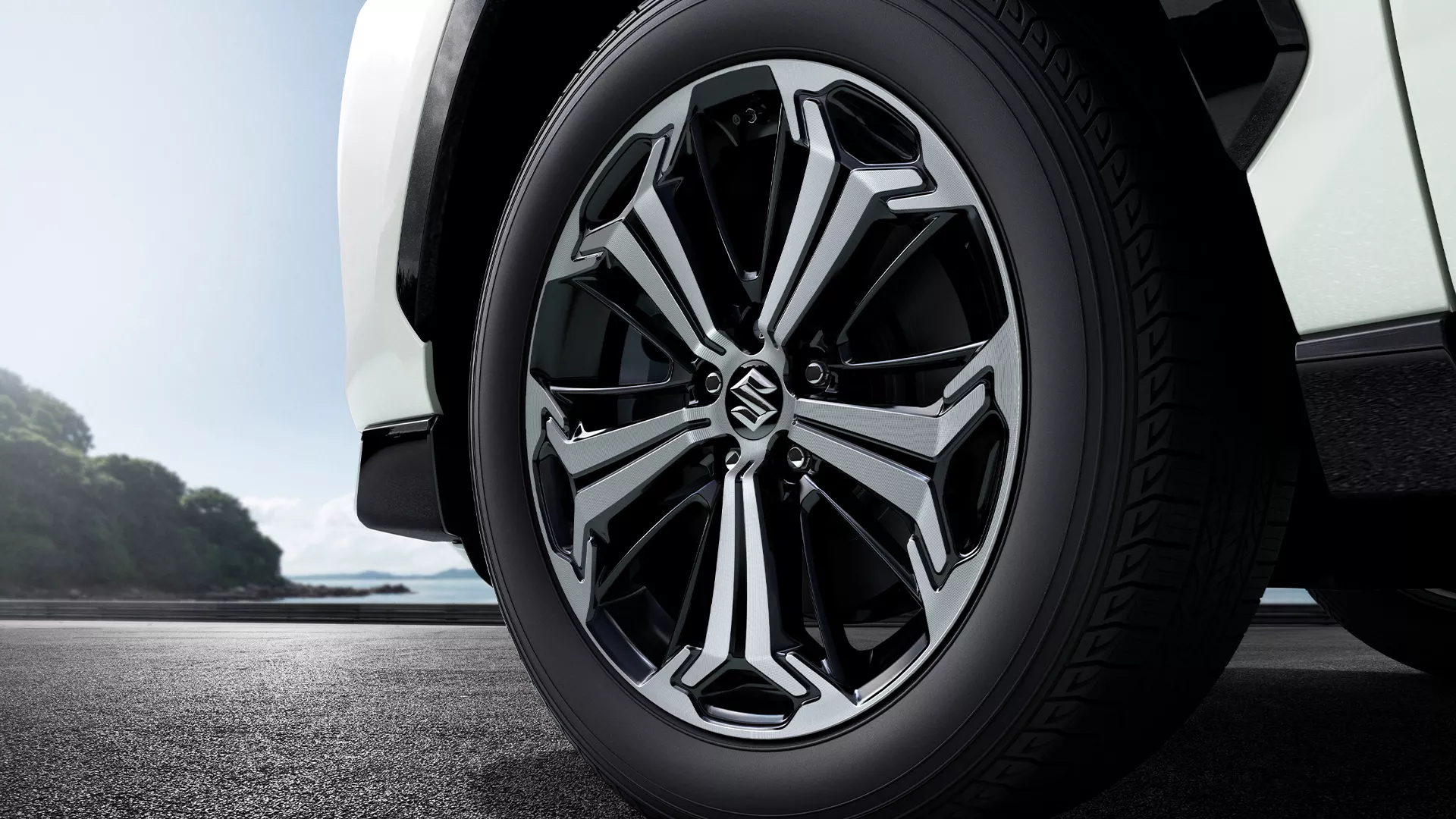 Close-up of Suzuki Across alloy wheel with precision-cut two-tone design and branded centre cap.