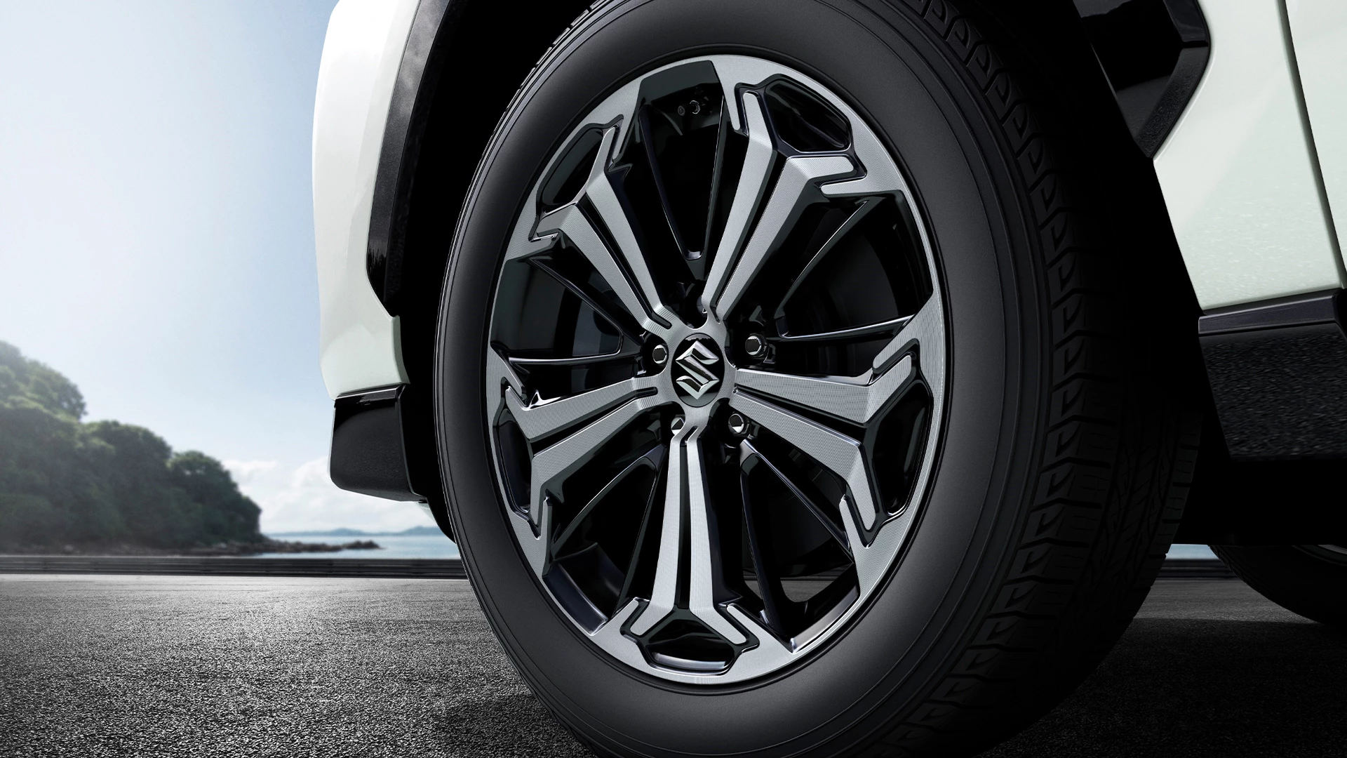 Close-up of Suzuki Across alloy wheel with precision-cut two-tone design and branded centre cap.