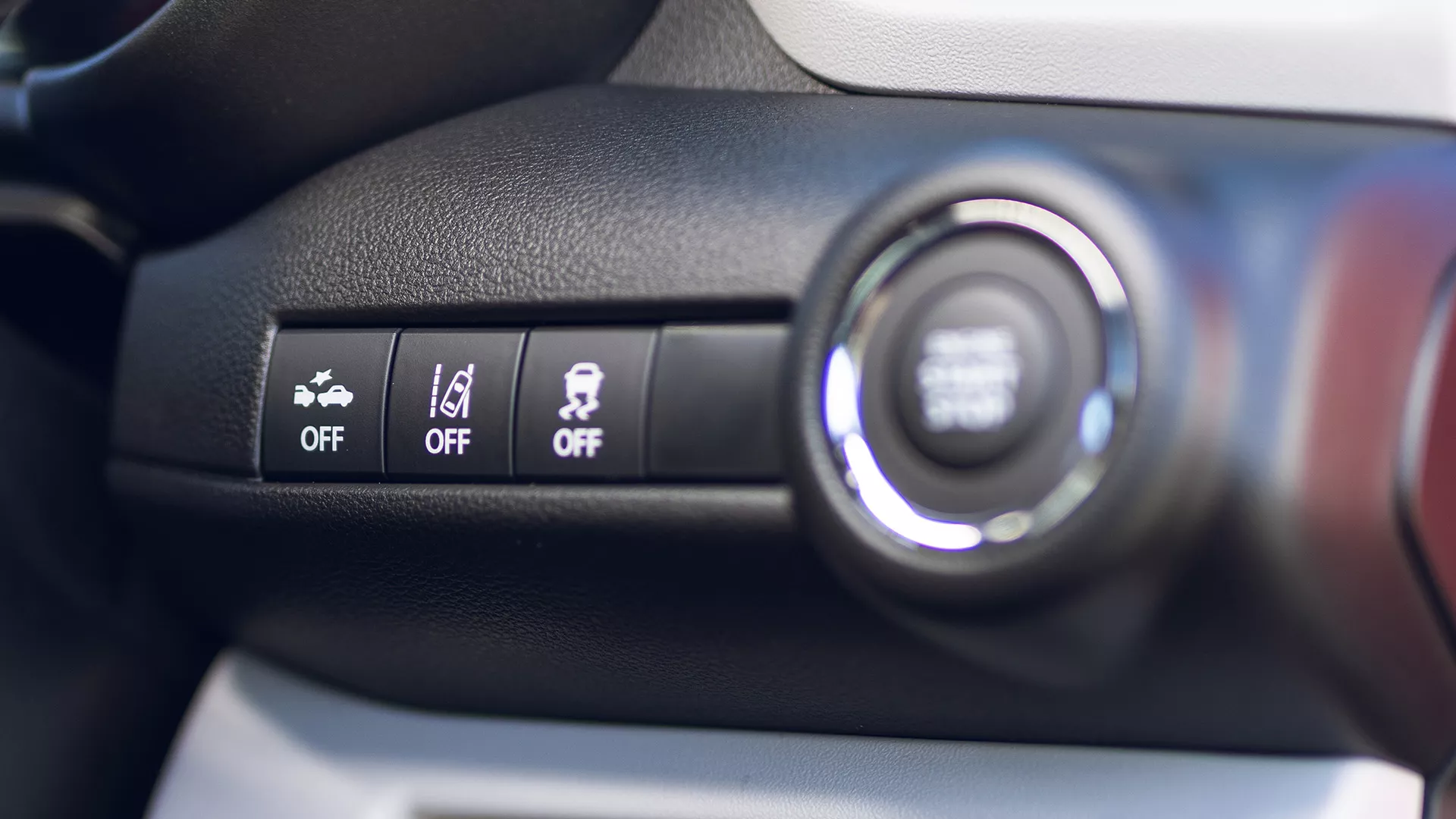 Close-up of Suzuki Swift dashboard safety control panel showing buttons for automatic emergency braking, lane departure warning, and stability control