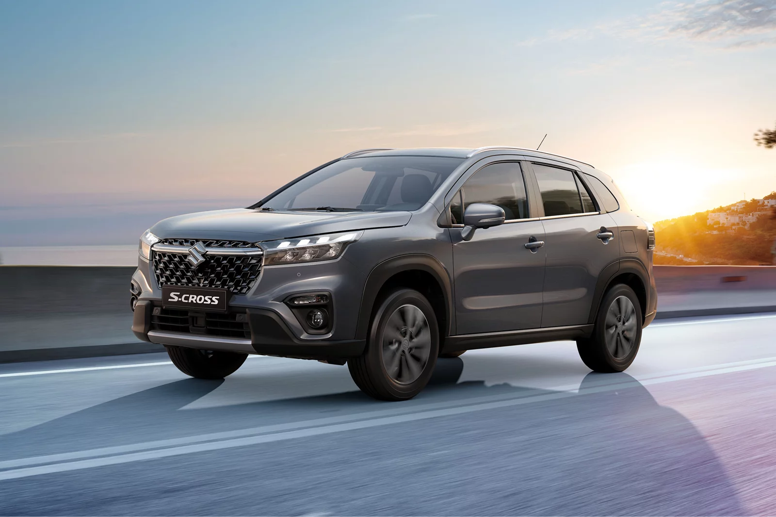Grey Suzuki S-Cross driving on a coastal road at sunset