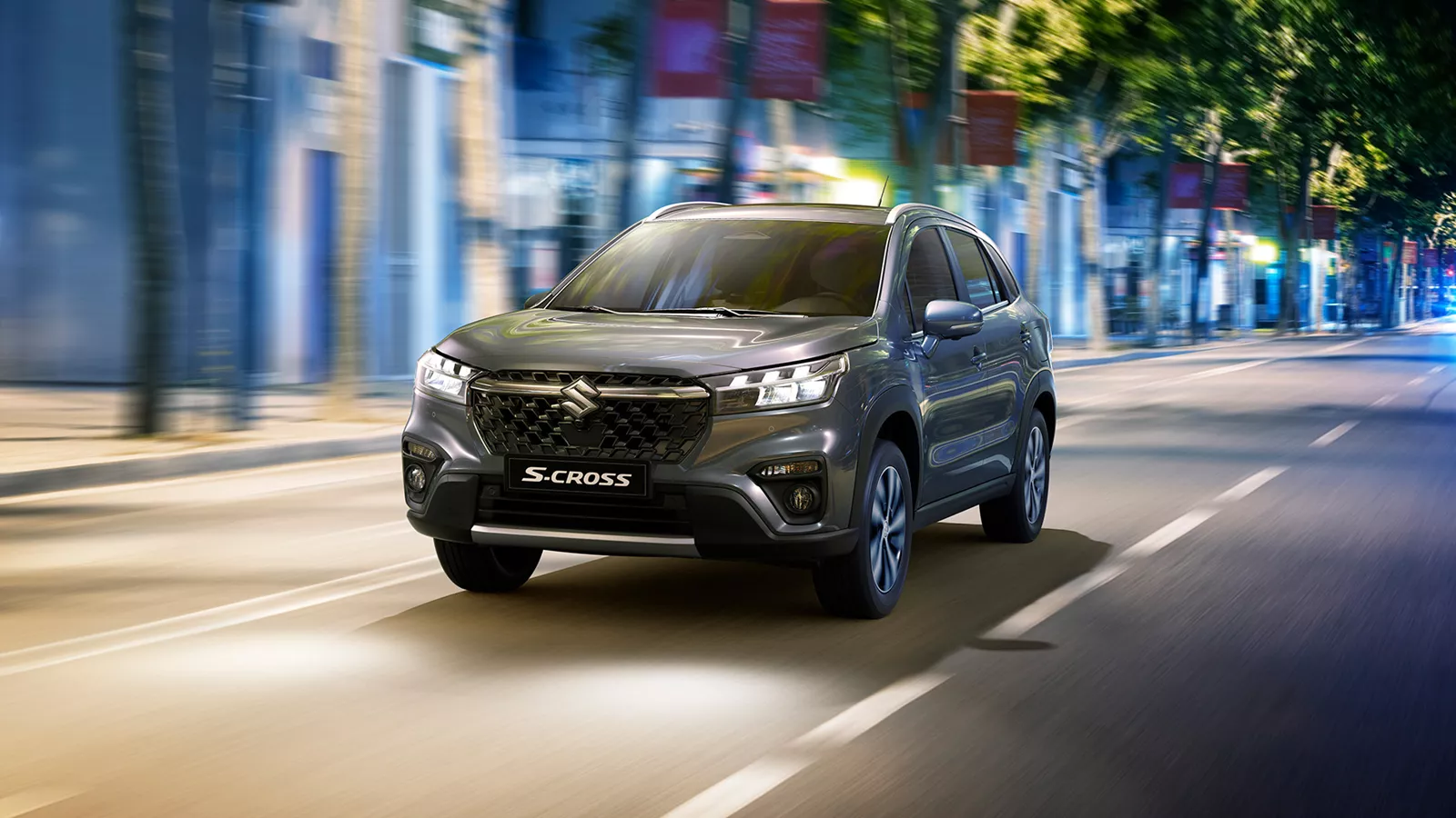 Titan grey Suzuki S-Cross driving through a vibrant city street, showcasing its confident styling and urban agility.