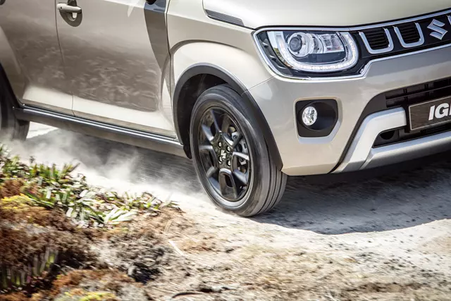 Close-up of the front right side of a Suzuki Ignis driving on a dirt road.