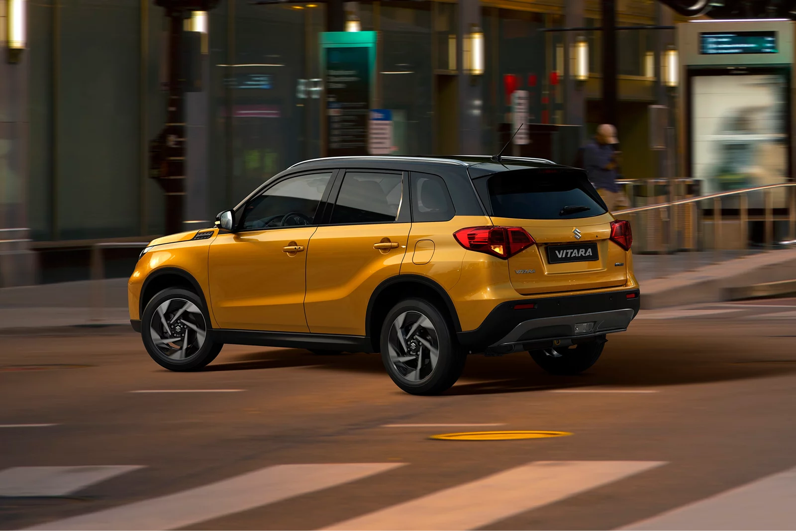 Yellow Suzuki Vitara driving through a city street at night