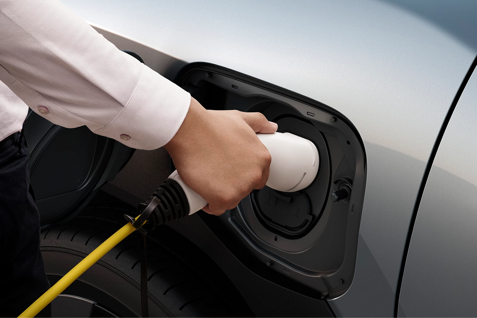 Hand connecting to a charging cable plugged into the charging port of a Suzuki e Vitara