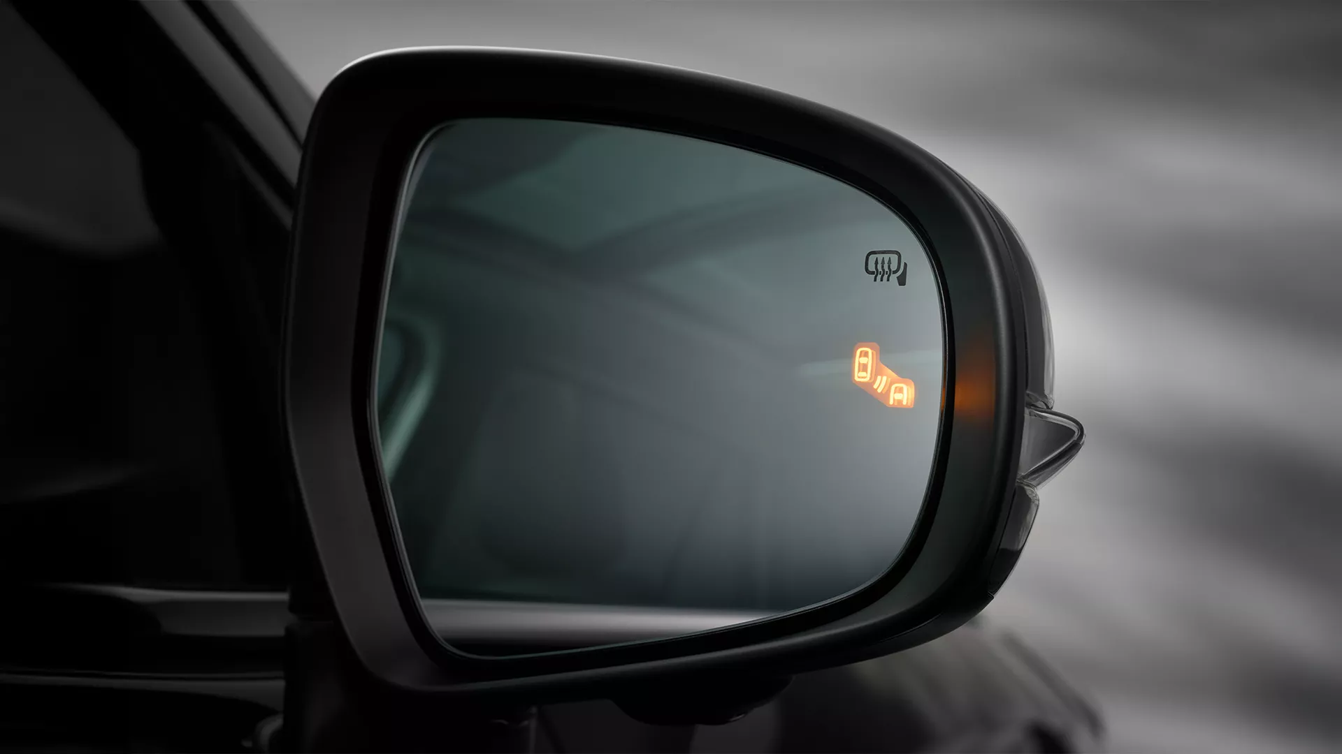 Suzuki e Vitara side mirror showing illuminated Blind Spot Monitor warning icon, indicating a vehicle in the adjacent lane