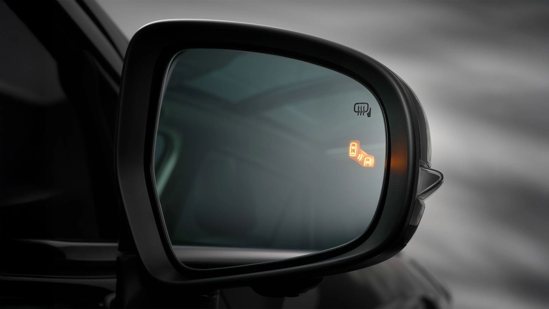 Suzuki e Vitara side mirror showing illuminated Blind Spot Monitor warning icon, indicating a vehicle in the adjacent lane