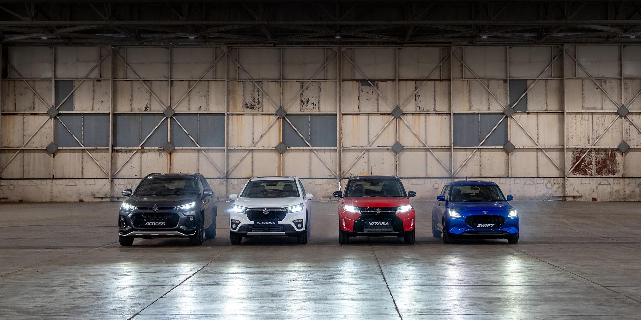 Suzuki Across, S-Cross, Vitara and Swift models parked inside an industrial warehouse