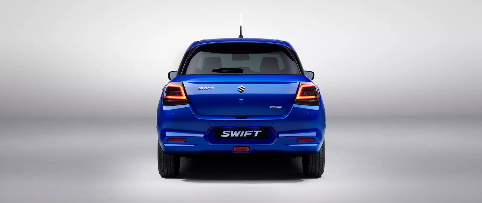 Rear view of the Suzuki Swift in frontier blue pearl metallic, showcasing the taillights, Swift badge, and modern hatchback design